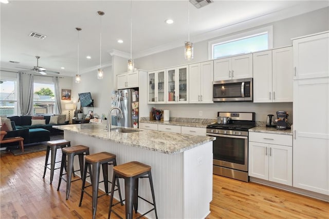 1723 N Broad St, New Orleans, LA 70119 - kitchen with appliances with stainless steel finishes, a sink, a breakfast bar, white cabinetry, and light wood-style floors
