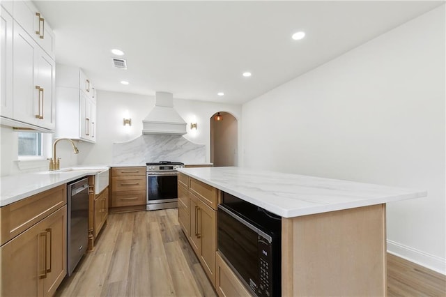 4412 Camel St, Metairie, LA 70001 - kitchen with appliances with stainless steel finishes, custom exhaust hood, a center island, light wood finished floors, and backsplash