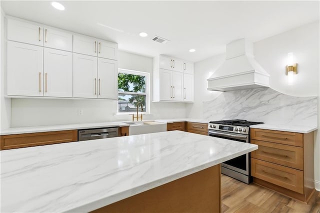 4412 Camel St, Metairie, LA 70001 - kitchen with custom range hood, stainless steel appliances, a sink, light stone countertops, and recessed lighting