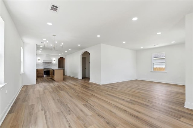 4412 Camel St, Metairie, LA 70001 - unfurnished living room with arched walkways, a chandelier, light wood-style flooring, recessed lighting, and baseboards