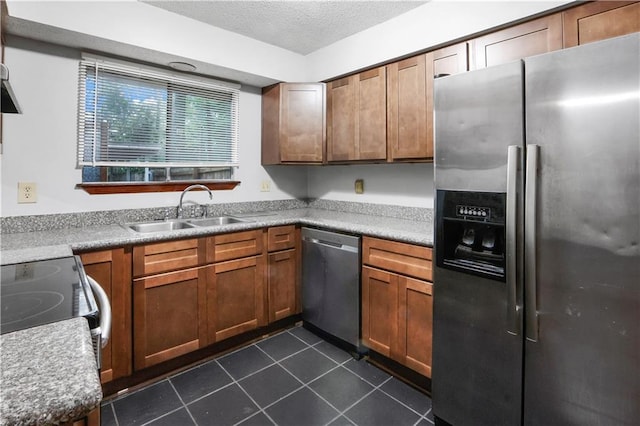 154 Oakwood Dr, Mandeville, LA 70448 - kitchen featuring stainless steel appliances, a sink, dark tile patterned flooring, a textured ceiling, and brown cabinets