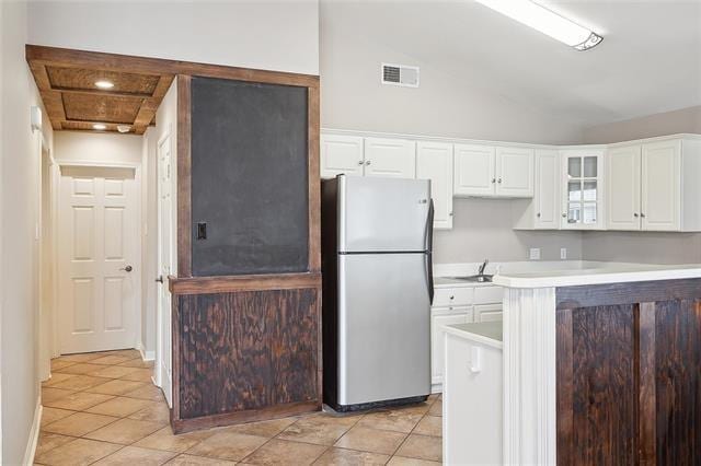 313 Celeste Ave, River Ridge, LA 70123 - kitchen featuring freestanding refrigerator, white cabinetry, glass insert cabinets, light countertops, and light tile patterned flooring
