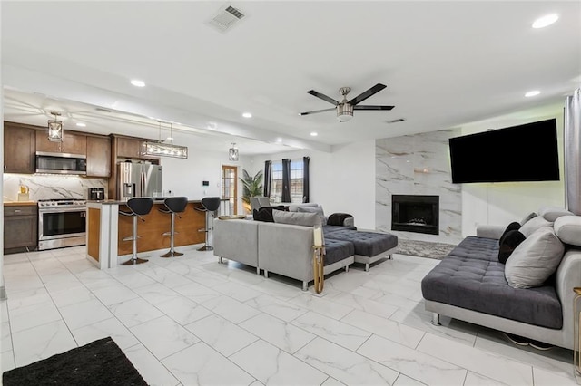 living room featuring light marble finish flooring, recessed lighting, ceiling fan, and a fireplace