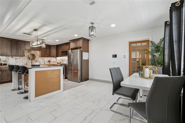 kitchen featuring stainless steel appliances, light marble finish floors, recessed lighting, a center island, and decorative light fixtures
