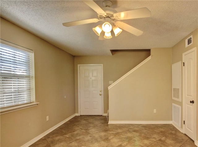 717 Heavens Dr Unit 4, Mandeville, LA 70471 - tiled empty room with a textured ceiling, stairs, ceiling fan, and baseboards