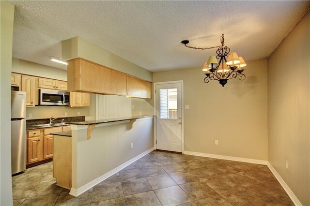717 Heavens Dr Unit 4, Mandeville, LA 70471 - kitchen featuring stainless steel appliances, dark countertops, a breakfast bar, a sink, and a peninsula