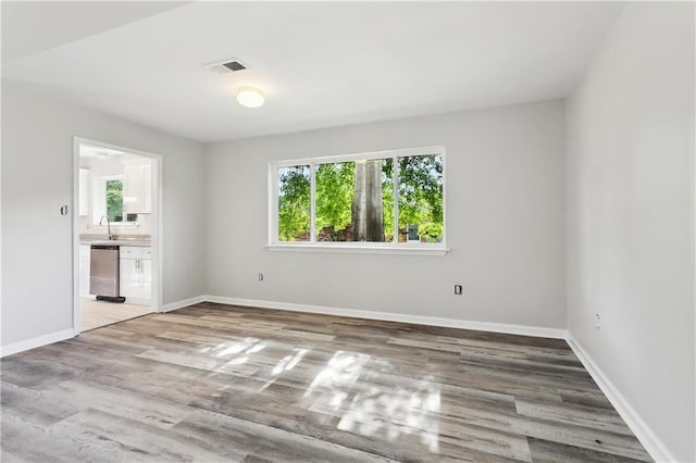 301 Holmes Dr, Slidell, LA 70460 - unfurnished bedroom with multiple windows, a sink, and wood finished floors