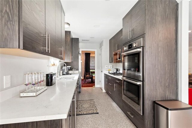 3928 Uri St, Metairie, LA 70002 - kitchen with appliances with stainless steel finishes, a sink, dark aggregate flooring, dark brown cabinetry, and light countertops
