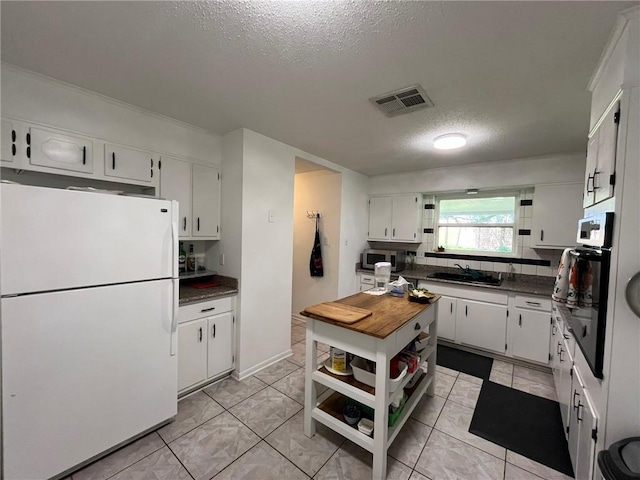 242 Willow Dr, Gretna, LA 70053 - kitchen featuring freestanding refrigerator, open shelves, stainless steel microwave, a sink, and a textured ceiling