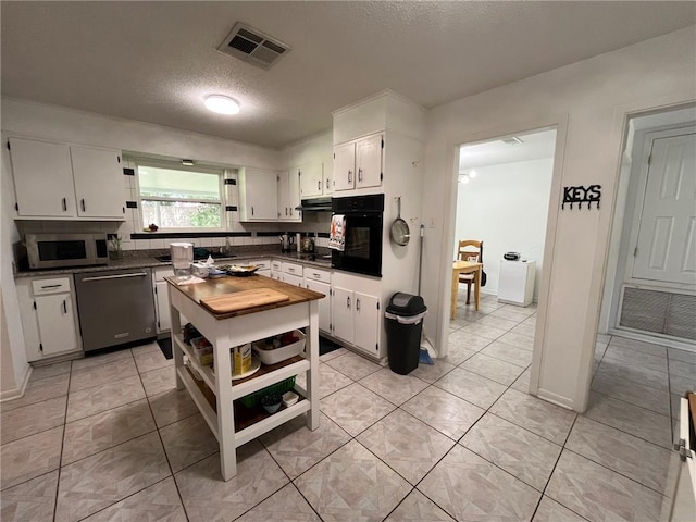 242 Willow Dr, Gretna, LA 70053 - kitchen with oven, stainless steel dishwasher, white cabinets, a textured ceiling, and under cabinet range hood