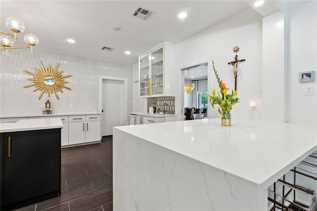 1201 N General Pershing St, Hammond, LA 70401 - kitchen with a chandelier, glass insert cabinets, white cabinets, dark wood-type flooring, and light stone counters