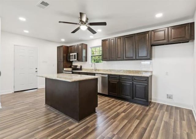 333 Killona Dr, Killona, LA 70057 - kitchen featuring appliances with stainless steel finishes, dark wood-type flooring, a ceiling fan, dark brown cabinets, and a center island