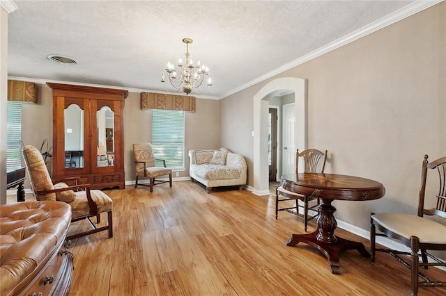 3851 Croydon St, Slidell, LA 70458 - living area featuring arched walkways, light wood-type flooring, a textured ceiling, a chandelier, and baseboards