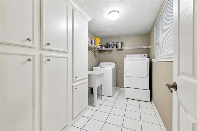 3851 Croydon St, Slidell, LA 70458 - laundry room featuring washing machine and clothes dryer, light tile patterned flooring, a textured ceiling, cabinet space, and baseboards