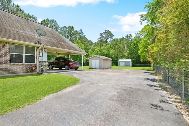 69359 6th Ave, Covington, LA 70433 - view of property exterior featuring a storage unit, asphalt driveway, an outbuilding, brick siding, and a shingled roof