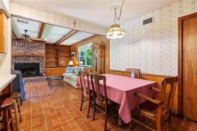 16 Ravan Ave, Harahan, LA 70123 - dining space with a ceiling fan, wooden walls, a wainscoted wall, brick patterned floors, and a fireplace