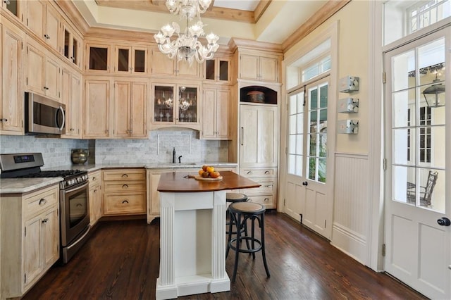 532-38 Governor Nicholls St, New Orleans, LA 70116 - kitchen featuring stainless steel appliances, a breakfast bar, light brown cabinets, healthy amount of natural light, and a wainscoted wall