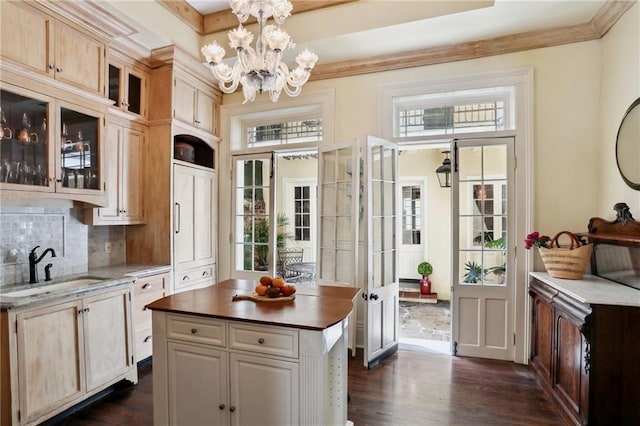 532-38 Governor Nicholls St, New Orleans, LA 70116 - kitchen featuring a sink, a chandelier, dark wood-style floors, glass insert cabinets, and decorative backsplash