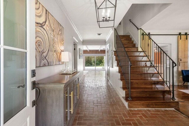 4 Riverdale Dr, Covington, LA 70433 - foyer with brick floors, stairs, a chandelier, crown molding, and a barn door