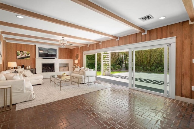 4 Riverdale Dr, Covington, LA 70433 - living area featuring wooden walls, beamed ceiling, a chandelier, a fireplace, and brick flooring