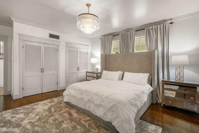 4 Riverdale Dr, Covington, LA 70433 - bedroom with multiple closets, crown molding, wood finished floors, and a chandelier