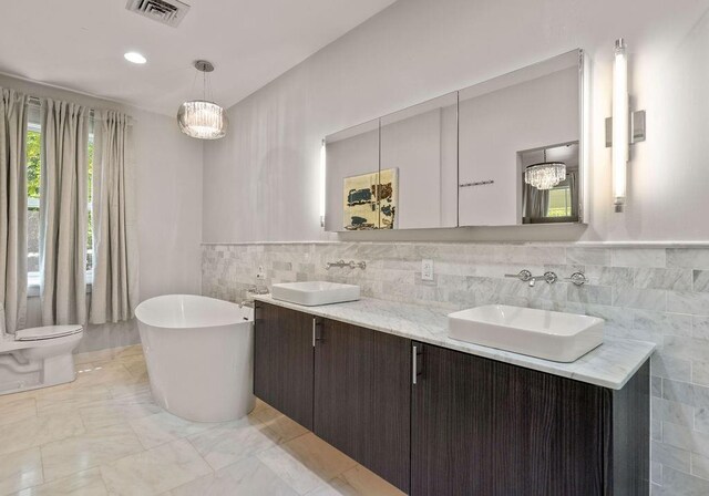 4 Riverdale Dr, Covington, LA 70433 - full bath with tile walls, double vanity, a freestanding tub, wainscoting, and marble finish floors