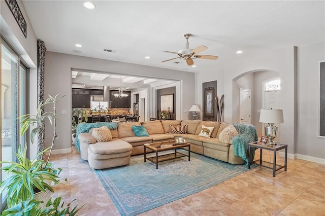 living area with a chandelier, a ceiling fan, arched walkways, recessed lighting, and baseboards