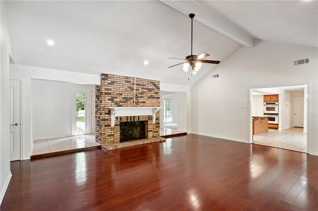 unfurnished living room with ceiling fan, a fireplace, light wood finished floors, healthy amount of natural light, and beamed ceiling