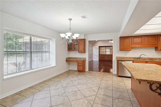 kitchen with stainless steel dishwasher, a chandelier, brown cabinets, decorative light fixtures, and light stone counters