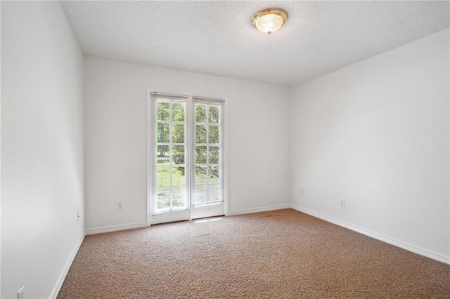 spare room with carpet floors, baseboards, and a textured ceiling