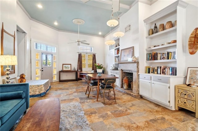 2000 St Philip St, New Orleans, LA 70116 - dining room featuring ornamental molding, a high ceiling, a fireplace with raised hearth, a ceiling fan, and built in features