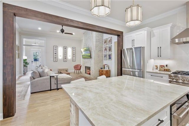 343 Saw Grass Loop, Covington, LA 70435 - kitchen with premium appliances, ornamental molding, wall chimney exhaust hood, light stone countertops, and white cabinetry