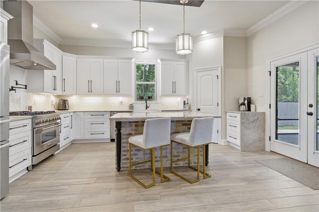 343 Saw Grass Loop, Covington, LA 70435 - kitchen featuring high end stainless steel range oven, wall chimney range hood, ornamental molding, light countertops, and a breakfast bar