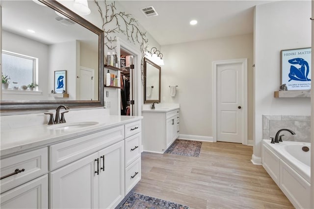 343 Saw Grass Loop, Covington, LA 70435 - full bathroom with two vanities, a bath, wood finished floors, recessed lighting, and a closet