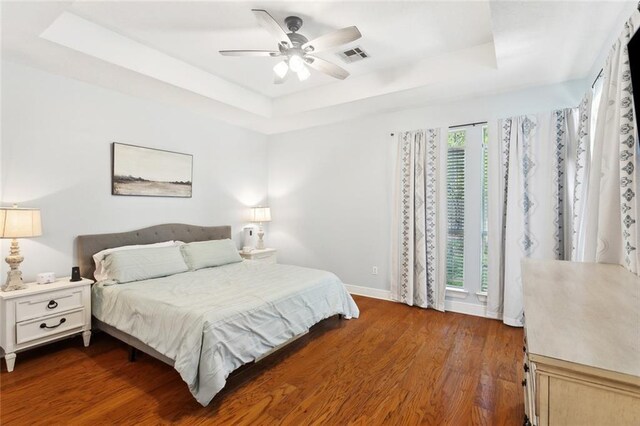 2107 Olvey Dr, Mandeville, LA 70448 - bedroom with a tray ceiling, dark wood finished floors, baseboards, and a ceiling fan