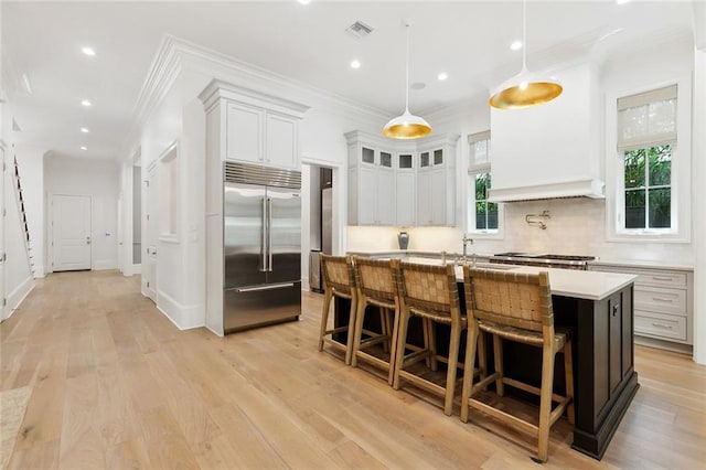 204 Vincent Ave, Metairie, LA 70005 - kitchen featuring appliances with stainless steel finishes, crown molding, light countertops, an island with sink, and a kitchen bar