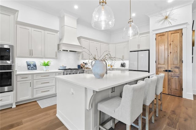 5072 Twin River Pl, Covington, LA 70433 - kitchen featuring appliances with stainless steel finishes, custom range hood, a kitchen island with sink, decorative backsplash, and light countertops