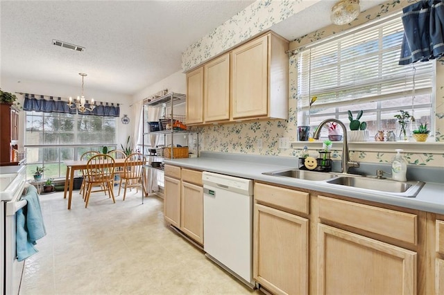 kitchen with white appliances, light brown cabinetry, a chandelier, a sink, and a textured ceiling