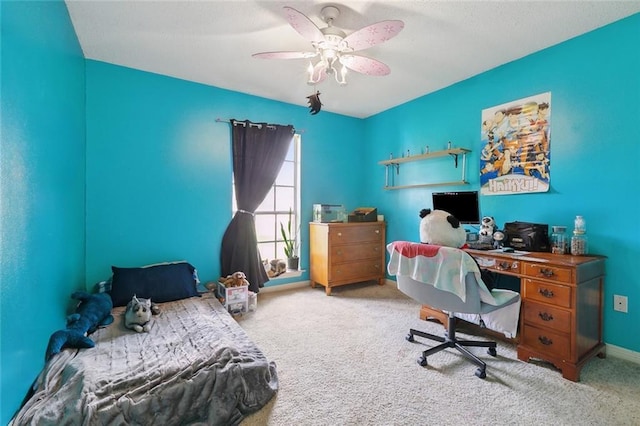 carpeted bedroom with ceiling fan, a desk, and baseboards