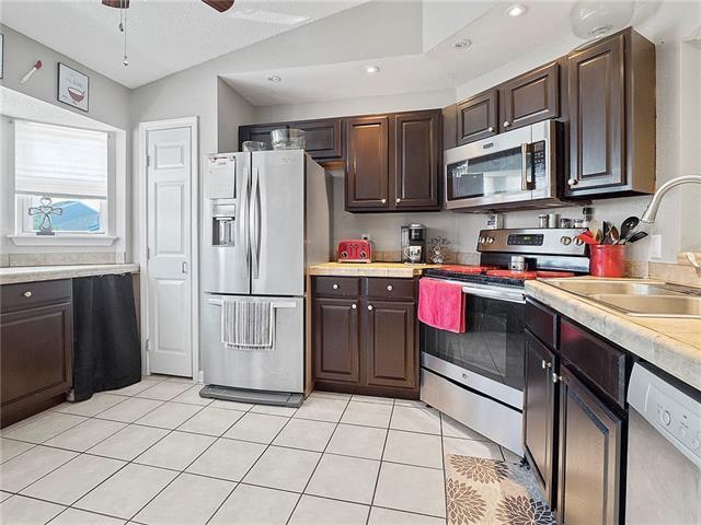 68 Avant Garde Cir Unit 68, Kenner, LA 70065 - kitchen with stainless steel appliances, light countertops, dark brown cabinets, light tile patterned floors, and recessed lighting
