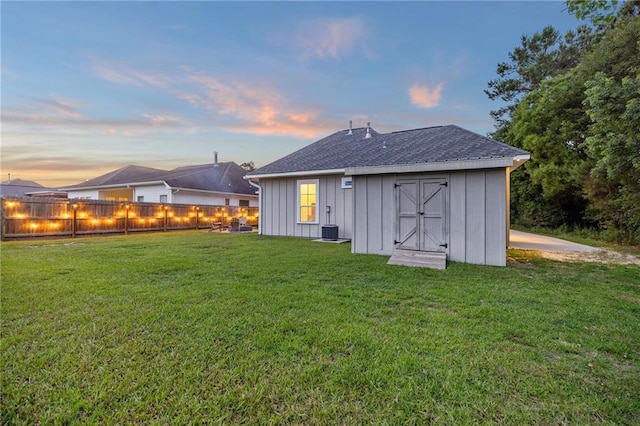1029 Spring Haven Ln, Madisonville, LA 70447 - rear view of property with board and batten siding, a yard, an outdoor structure, roof with shingles, and central AC