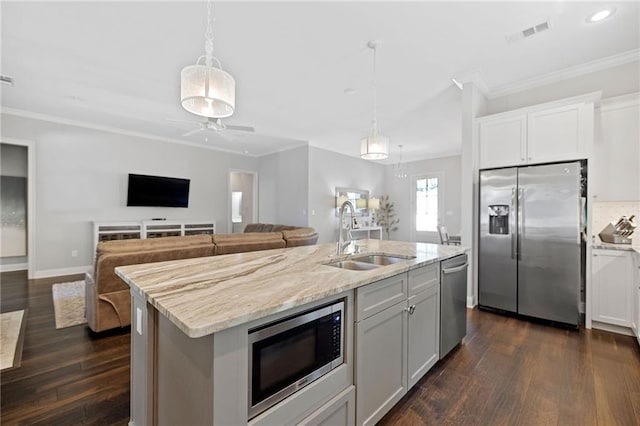 1029 Spring Haven Ln, Madisonville, LA 70447 - kitchen featuring stainless steel appliances, a sink, ornamental molding, light stone counters, and dark wood finished floors