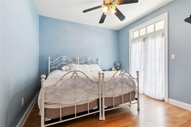 bedroom featuring baseboards, wood finished floors, and ceiling fan