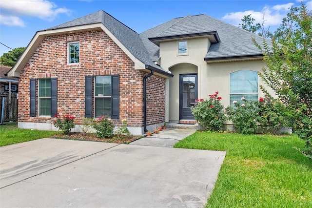 3225 Delaware Ave, Kenner, LA 70065 - view of front of home with brick siding, a front lawn, a shingled roof, and stucco siding