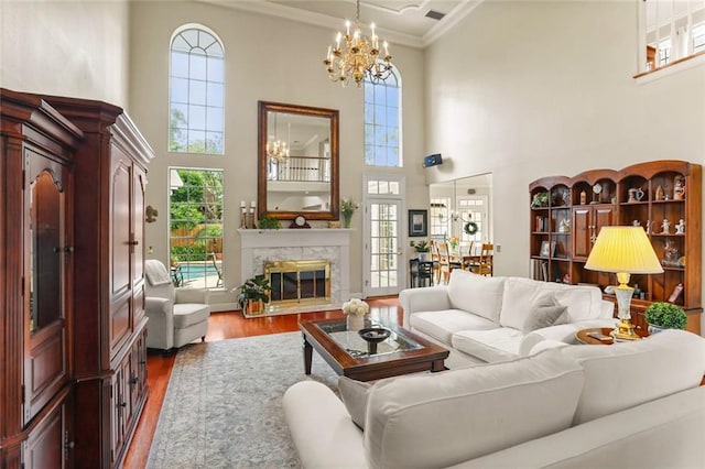137 Lakewood Estates Dr, New Orleans, LA 70131 - living room featuring a high ceiling, wood finished floors, ornamental molding, a chandelier, and a high end fireplace