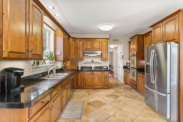137 Lakewood Estates Dr, New Orleans, LA 70131 - kitchen with appliances with stainless steel finishes, a sink, under cabinet range hood, brown cabinetry, and dark countertops