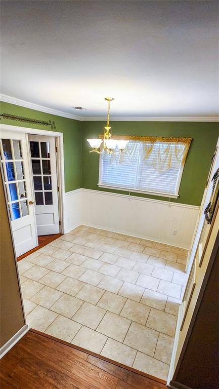 1513 Mason Smith Ave, Metairie, LA 70003 - spare room featuring ornamental molding, wainscoting, a chandelier, and light tile patterned floors
