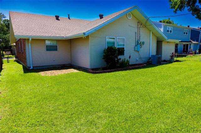 1513 Mason Smith Ave, Metairie, LA 70003 - rear view of house featuring a lawn, roof with shingles, and central AC