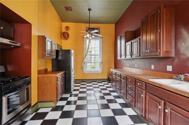 271214 Burgundy St, New Orleans, LA 70117 - kitchen featuring appliances with stainless steel finishes, dark flooring, under cabinet range hood, a ceiling fan, and light countertops