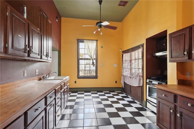 271214 Burgundy St, New Orleans, LA 70117 - kitchen featuring a ceiling fan, white gas range, dark flooring, butcher block counters, and dark brown cabinets